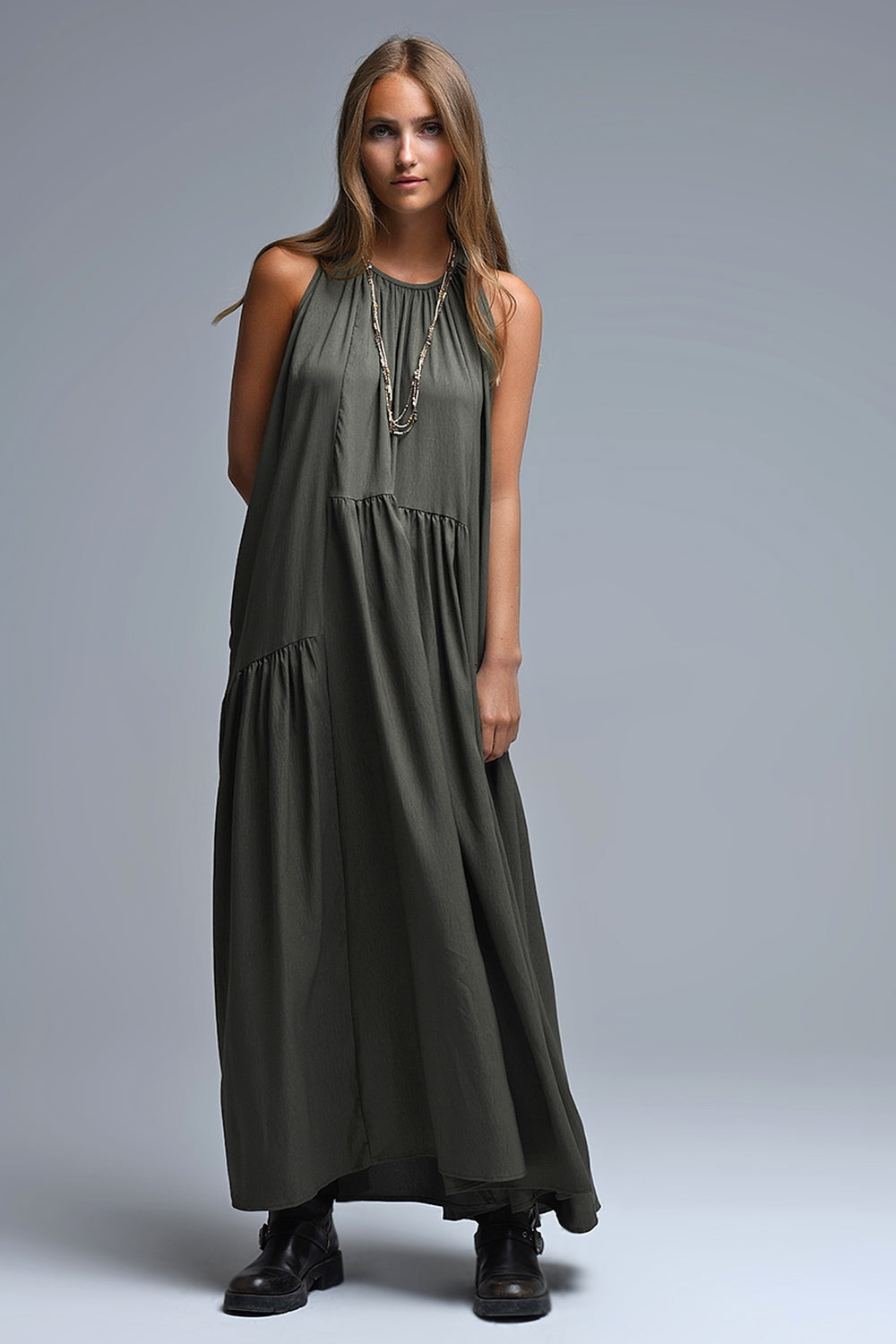 Vestido largo de color verde caqui con cuello halter y silueta maxi muy holgada, paneles fruncidos fluidos y bolsillos laterales ocultos.