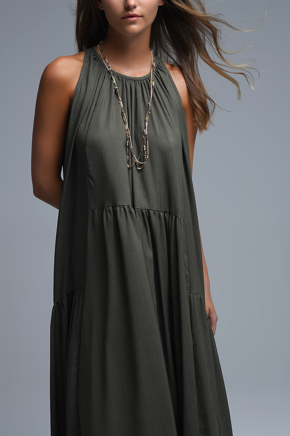 Vestido largo de color verde caqui con cuello halter y silueta maxi muy holgada, paneles fruncidos fluidos y bolsillos laterales ocultos.