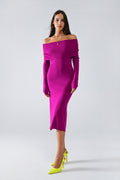 Modelo con vestido midi de punto ajustado en color magenta, con escote Bardot que deja los hombros al descubierto.