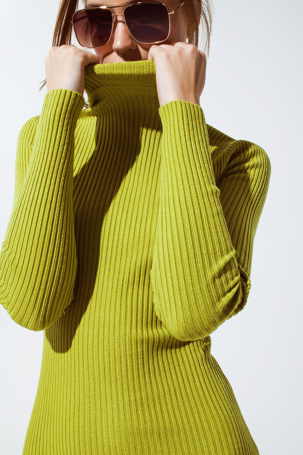 Modelo con vestido midi de punto ajustado y cuello tortuga en color verde lima o chartreuse.