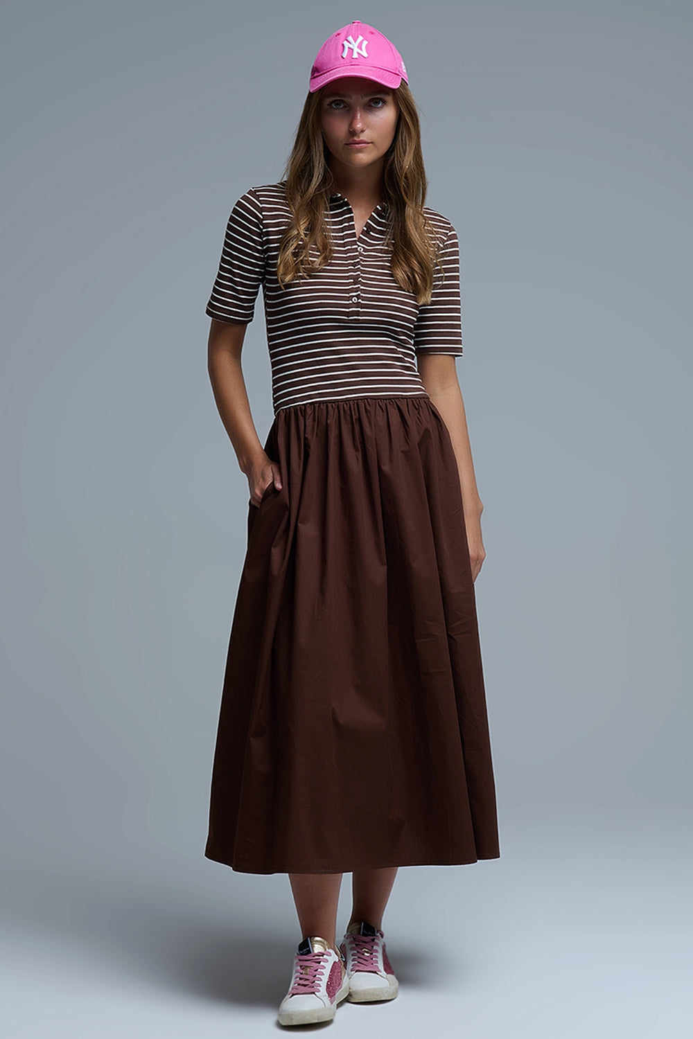 Mujer con vestido rayado marrón y gorra, look sporty urbano