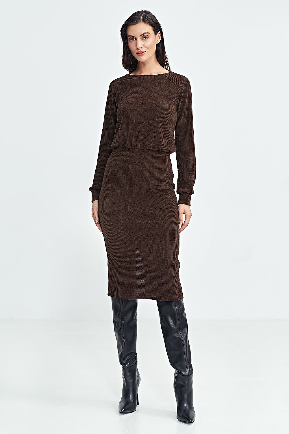 Modelo con vestido midi de punto acanalado en color marrón chocolate de efecto dos piezas, combinado con botas altas de cuero negras.