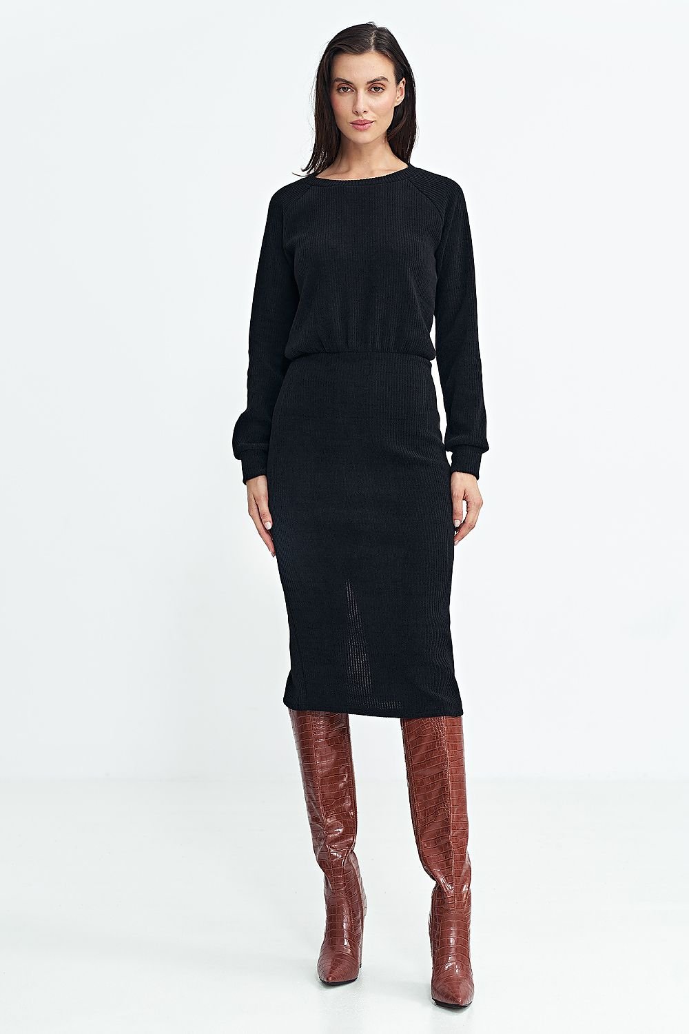 Modelo con vestido midi de punto acanalado negro de efecto dos piezas y botas altas marrones.