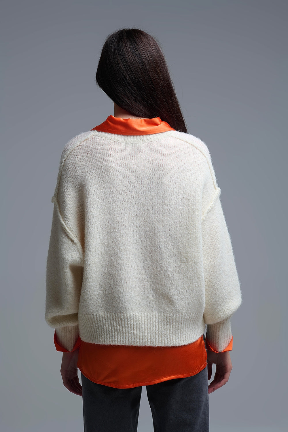 Vista trasera de un jersey de punto crema oversize, mostrando el fit amplio.