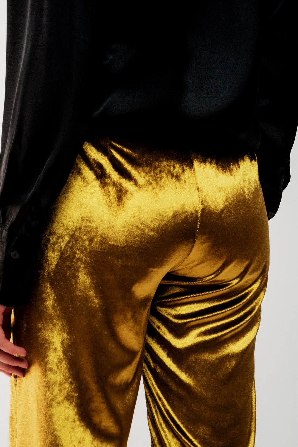 Parte trasera de unos pantalones de terciopelo lima brillante con caída fluida.