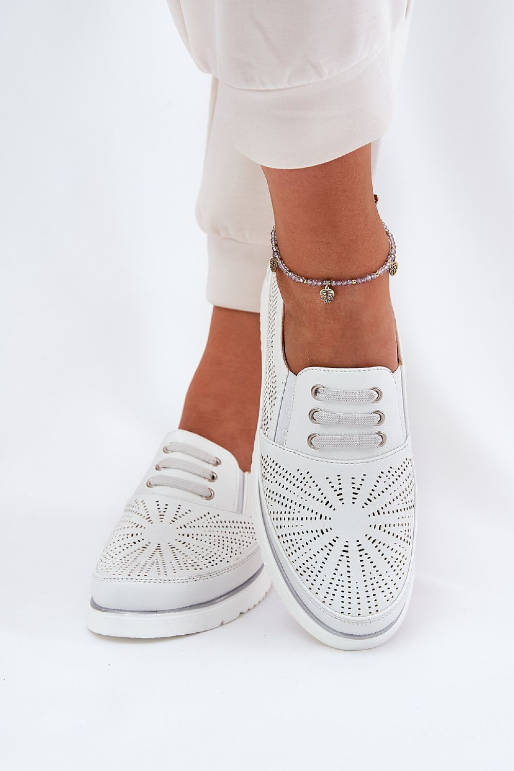 Look completo de zapatillas blancas de piel con diseño perforado y joggers crema.