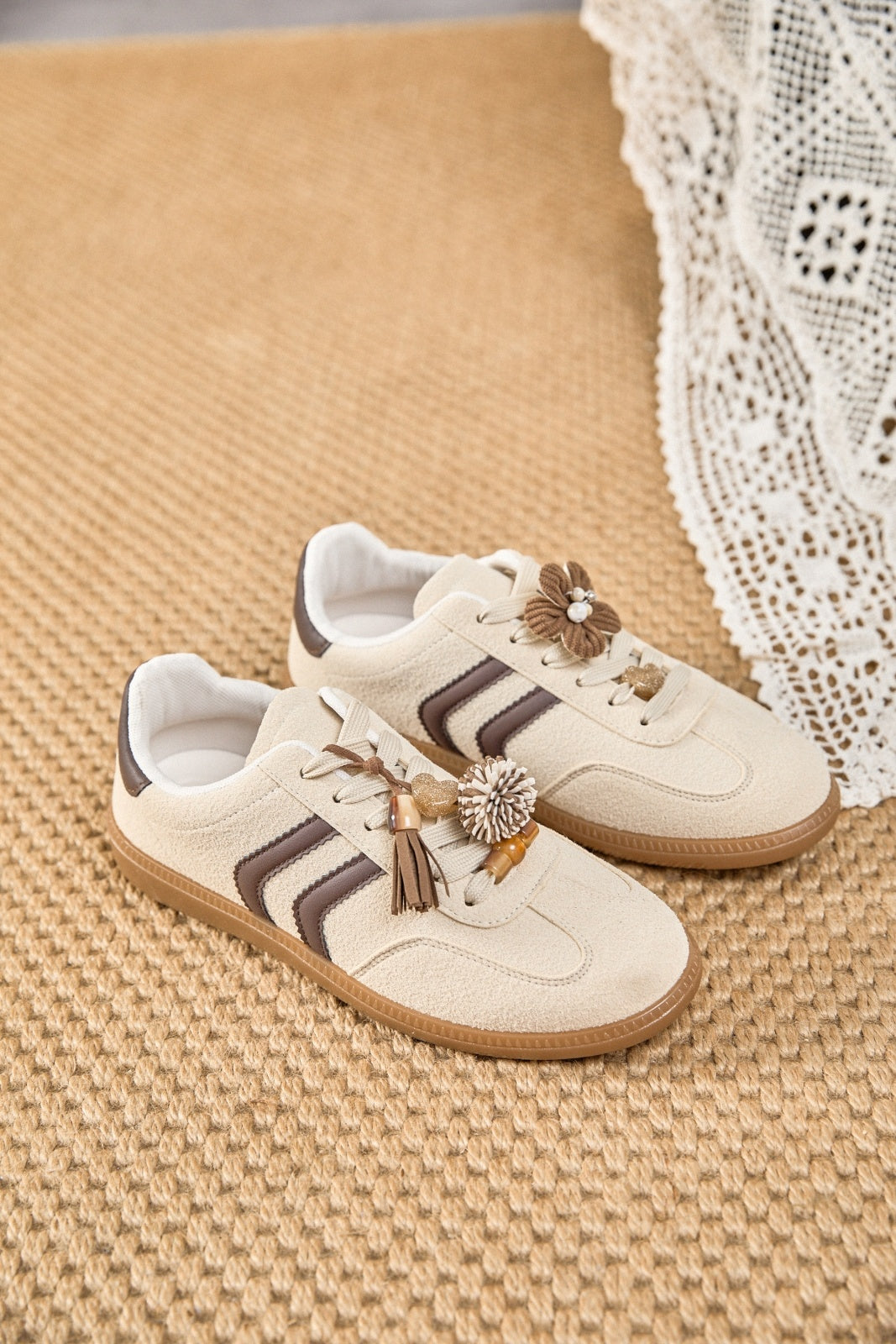 Zapatillas deportivas de mujer estilo retro en ante color crema con franjas marrón chocolate, suela de goma caramelo y detalles de flores 3D.