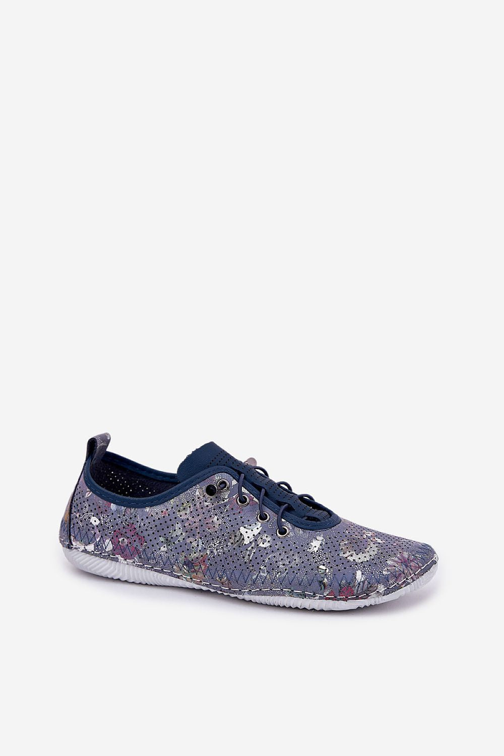 Zapatillas de piel en azul marino con estampado floral metalizado y elásticos, con pantalón blanco arrugado