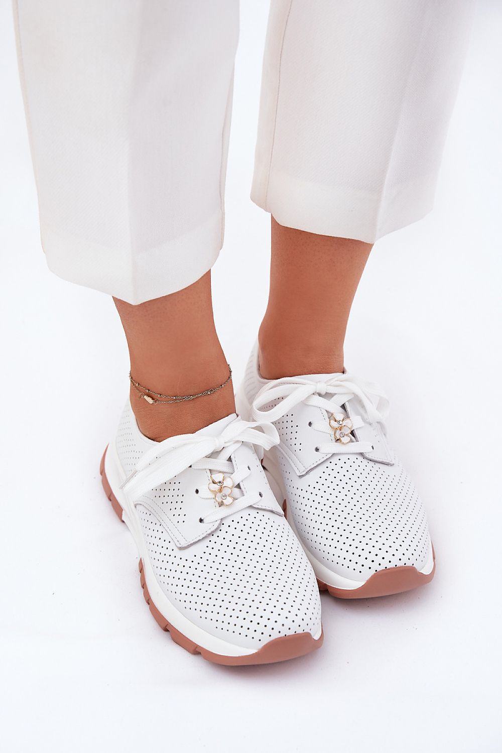 Zapatillas blancas con pantalón claro, detalle de cordones con flor
