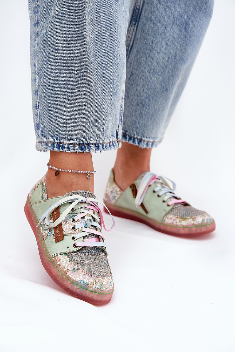 Mujer con vaqueros mostrando zapatillas Maciejka multicolor con cordones .