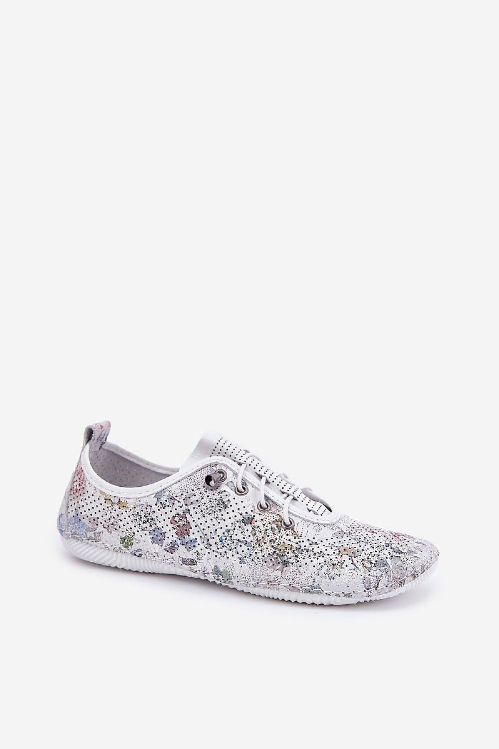 Zapatillas de piel blanca con detalles florales , vista lateral en conjunto con pantalón fluido blanco.