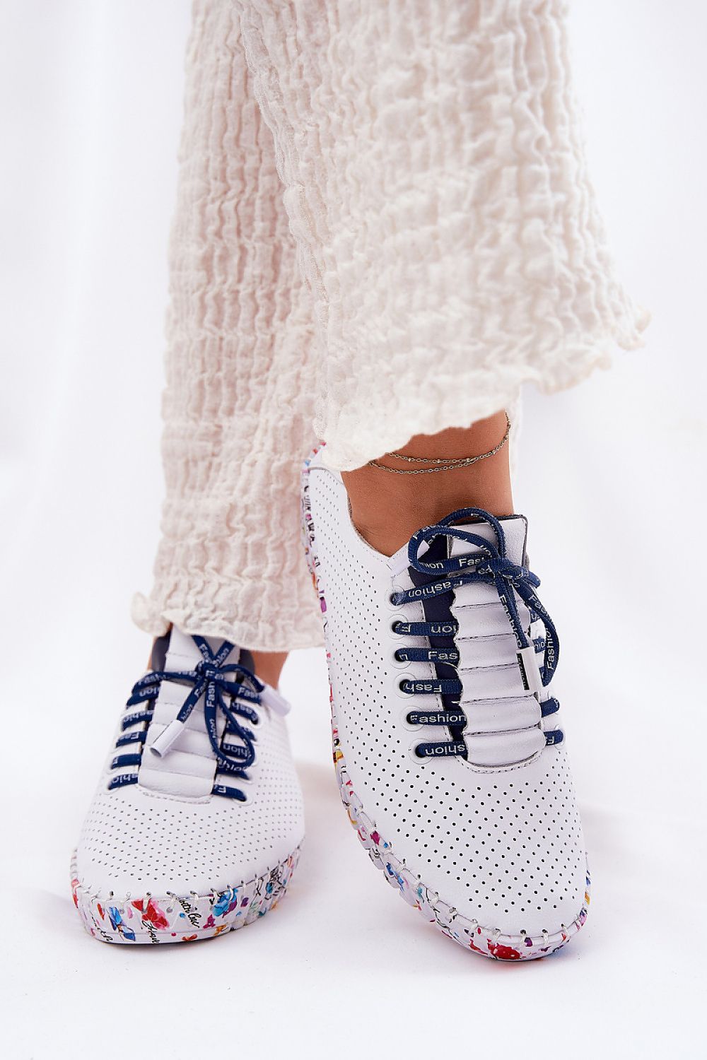  Zapatillas blancas de piel con cordones azul marino y suela estampada vista desde el frente